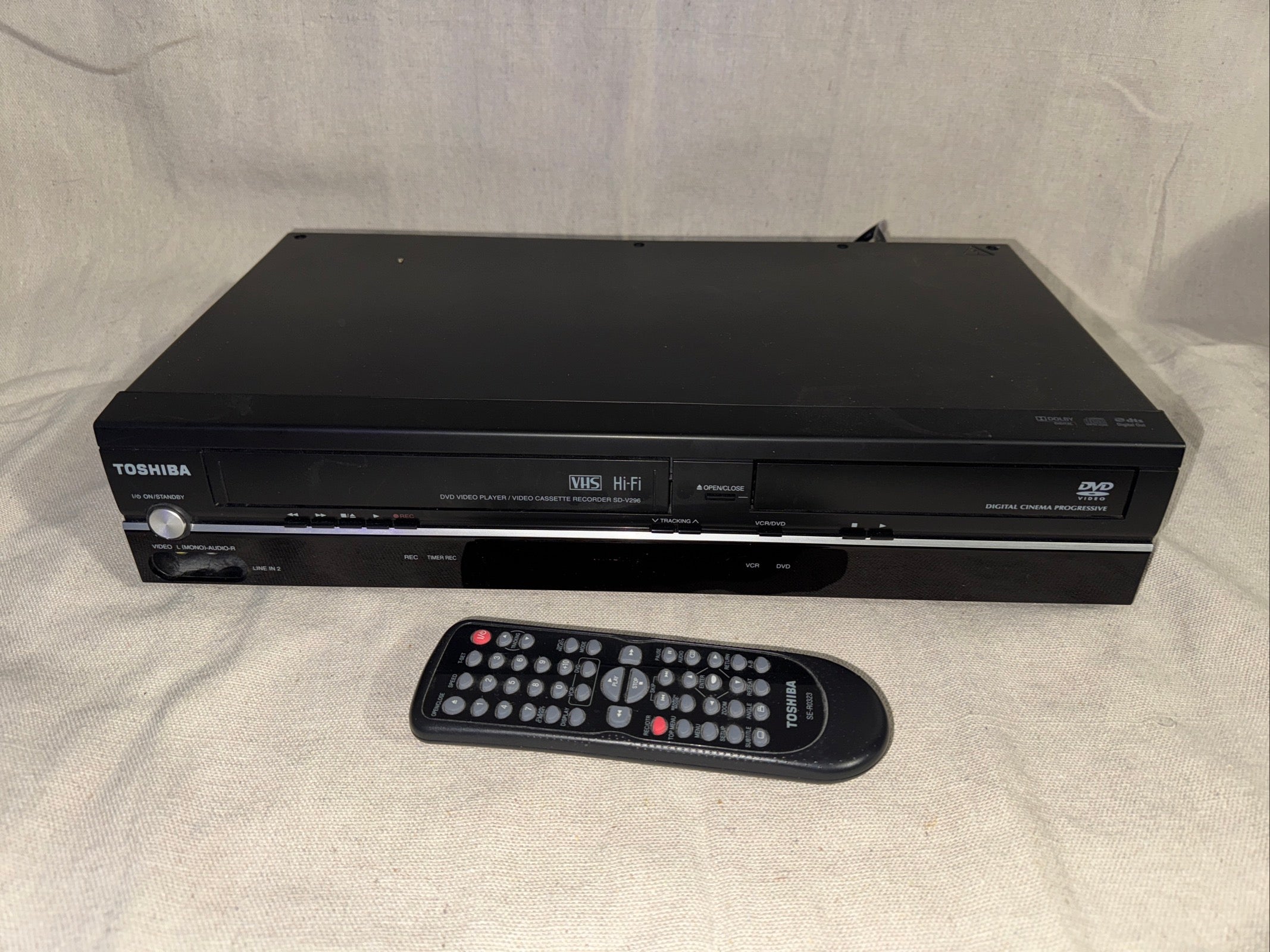 Serviced Toshiba SD-V296 DVD VHS Recorder With Remote on a beige background with remote control.