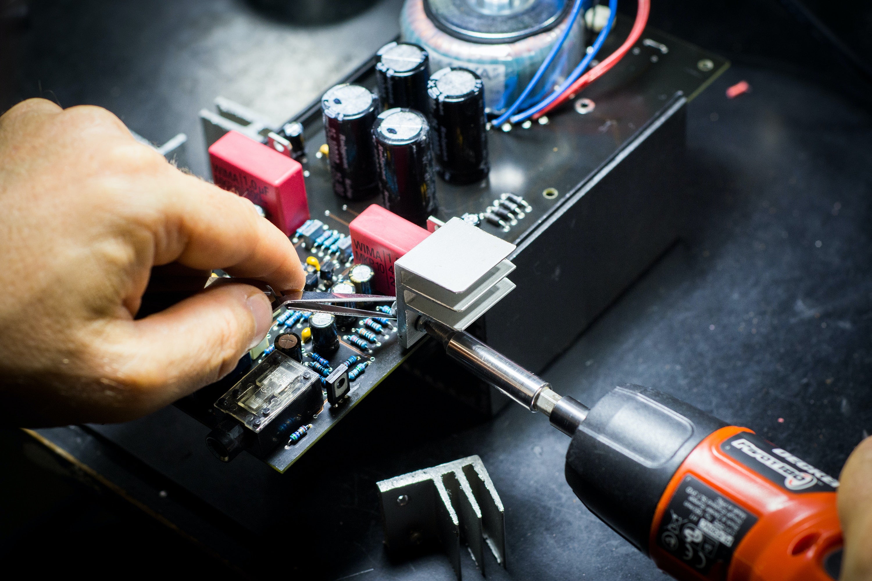 Technician repairing electronic equipment with tools, focusing on components for Mail In Electronic Equipment Service Estimate.