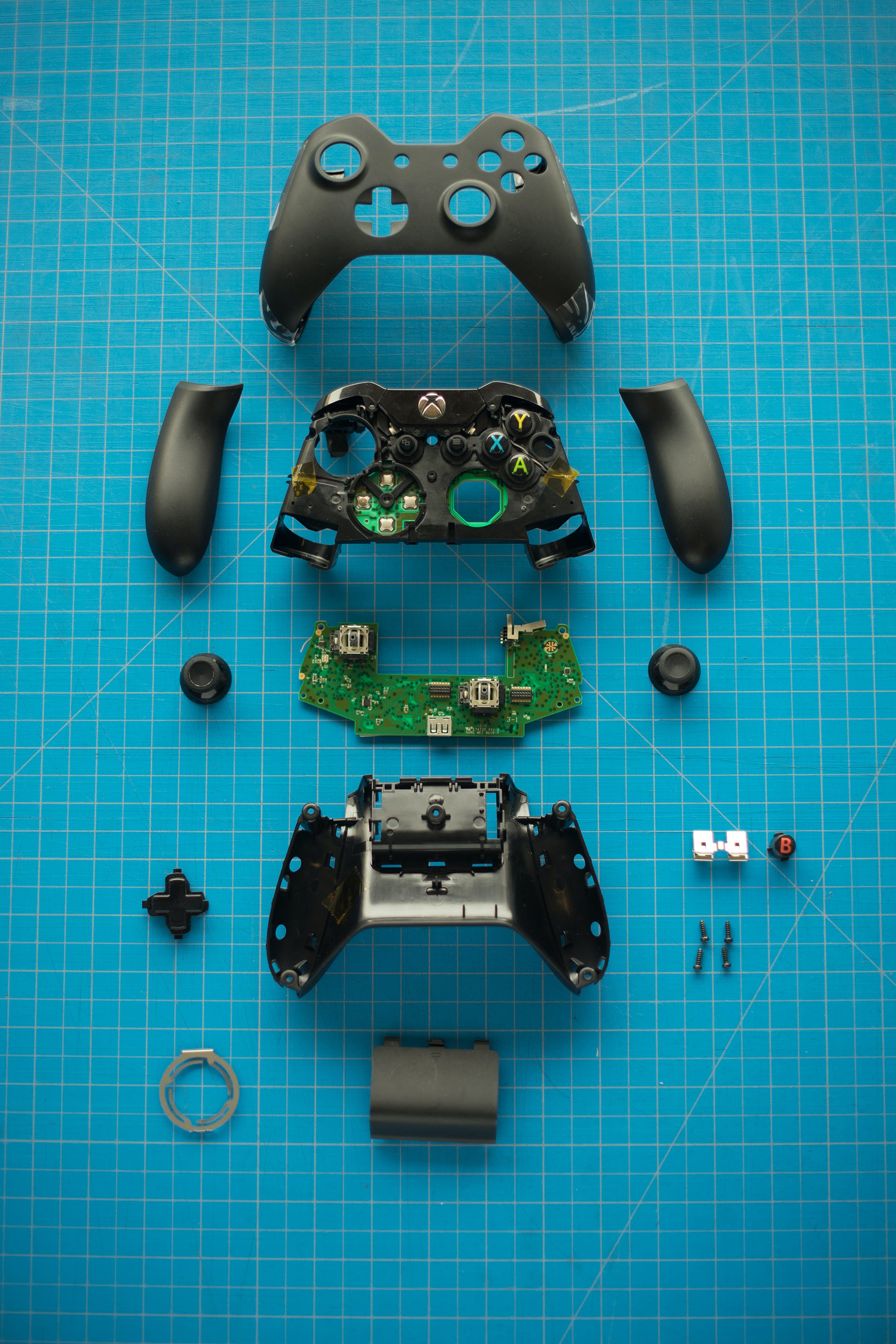 Mail In Repair Service For XBox One 360 PS5 PS4 PS3 Controller Sony Playstation Microsoft parts disassembled on blue background.
