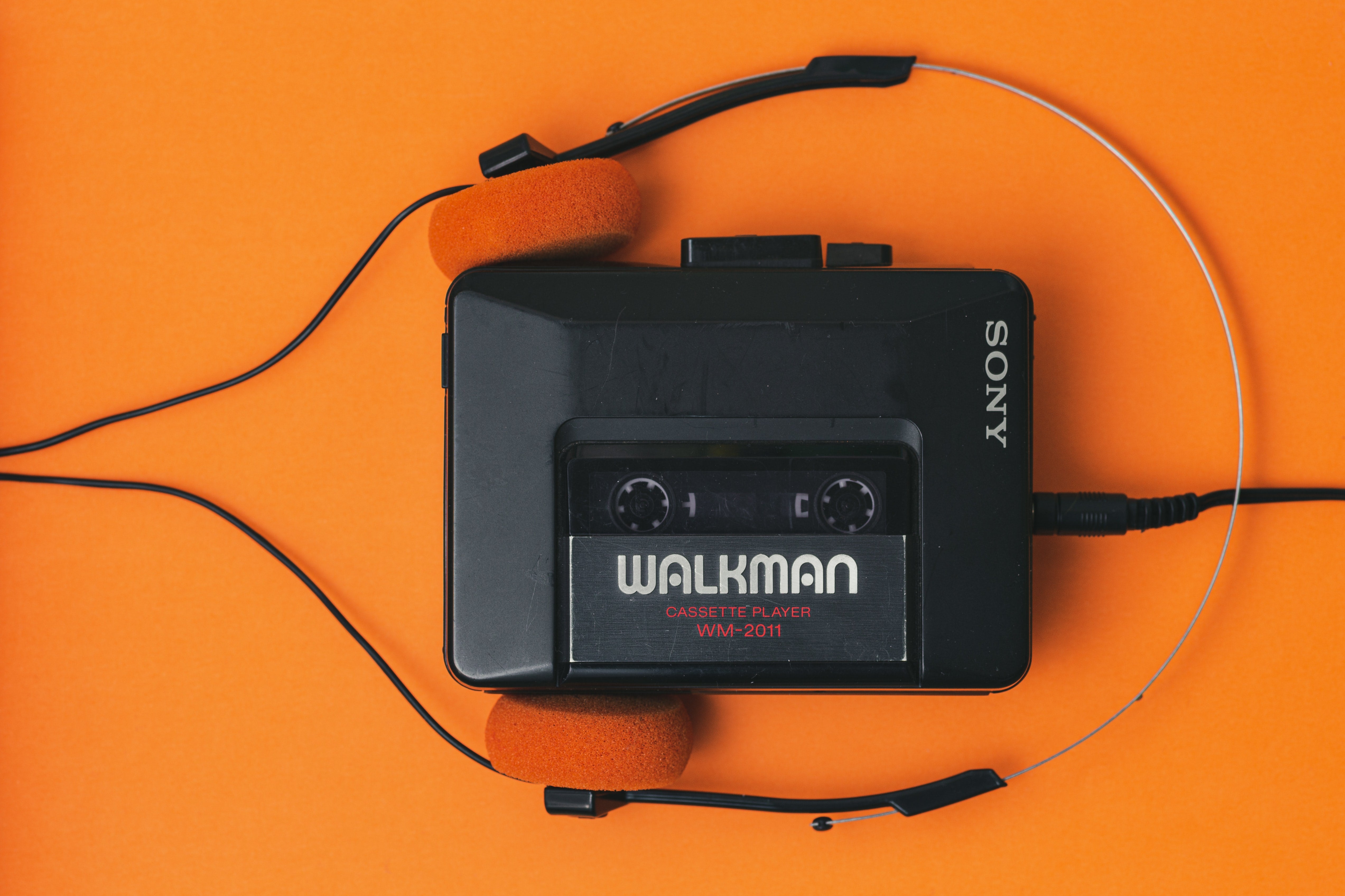 Repair Service for Sony Walkman and Portable Cassette Players - Sony Walkman on orange background with headphones.